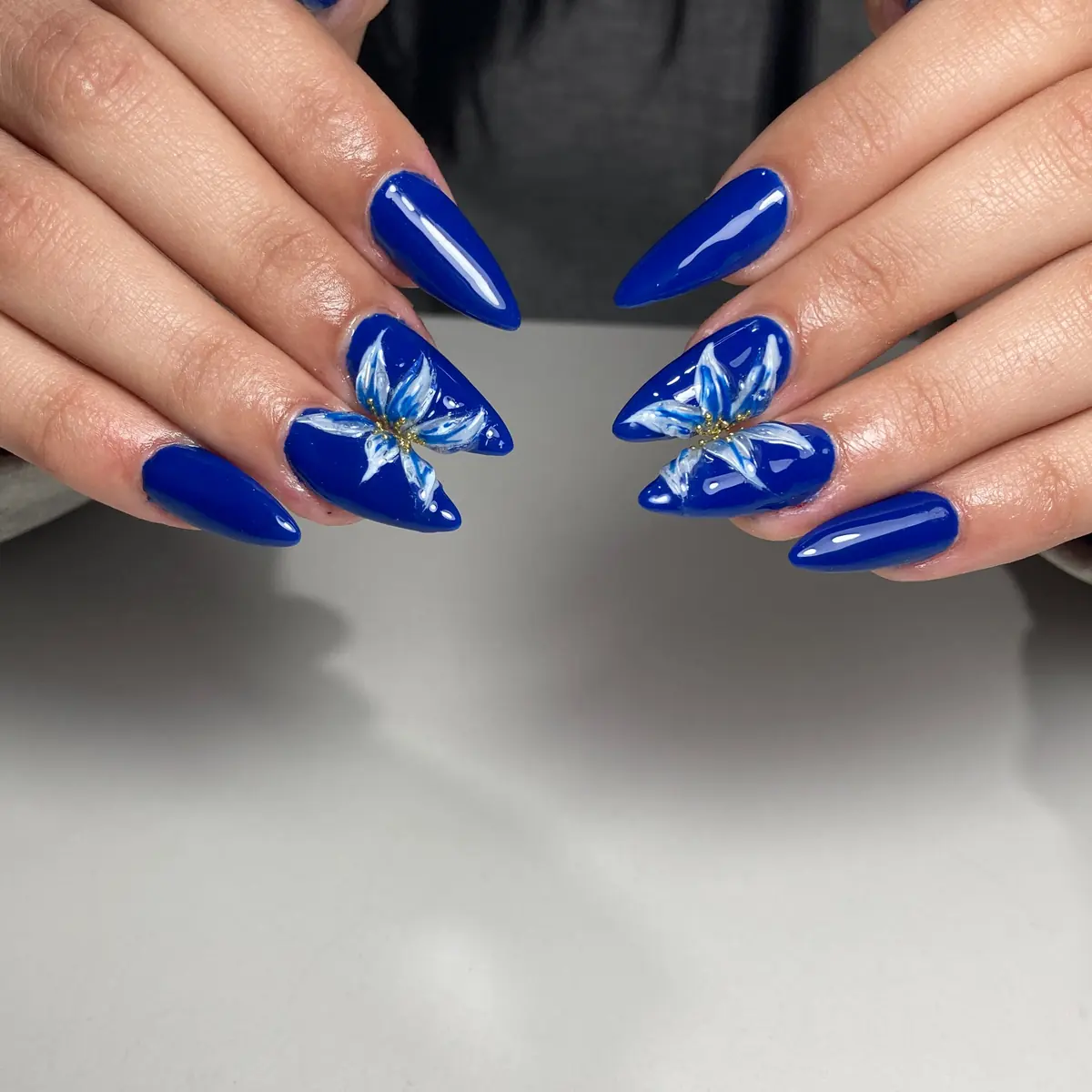 Uñas stiletto azules con flor pintada a mano